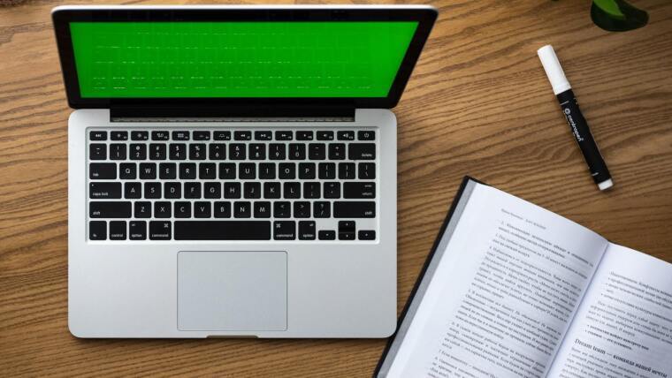 Laptop, Buch und Stift, von oben fotografiert
